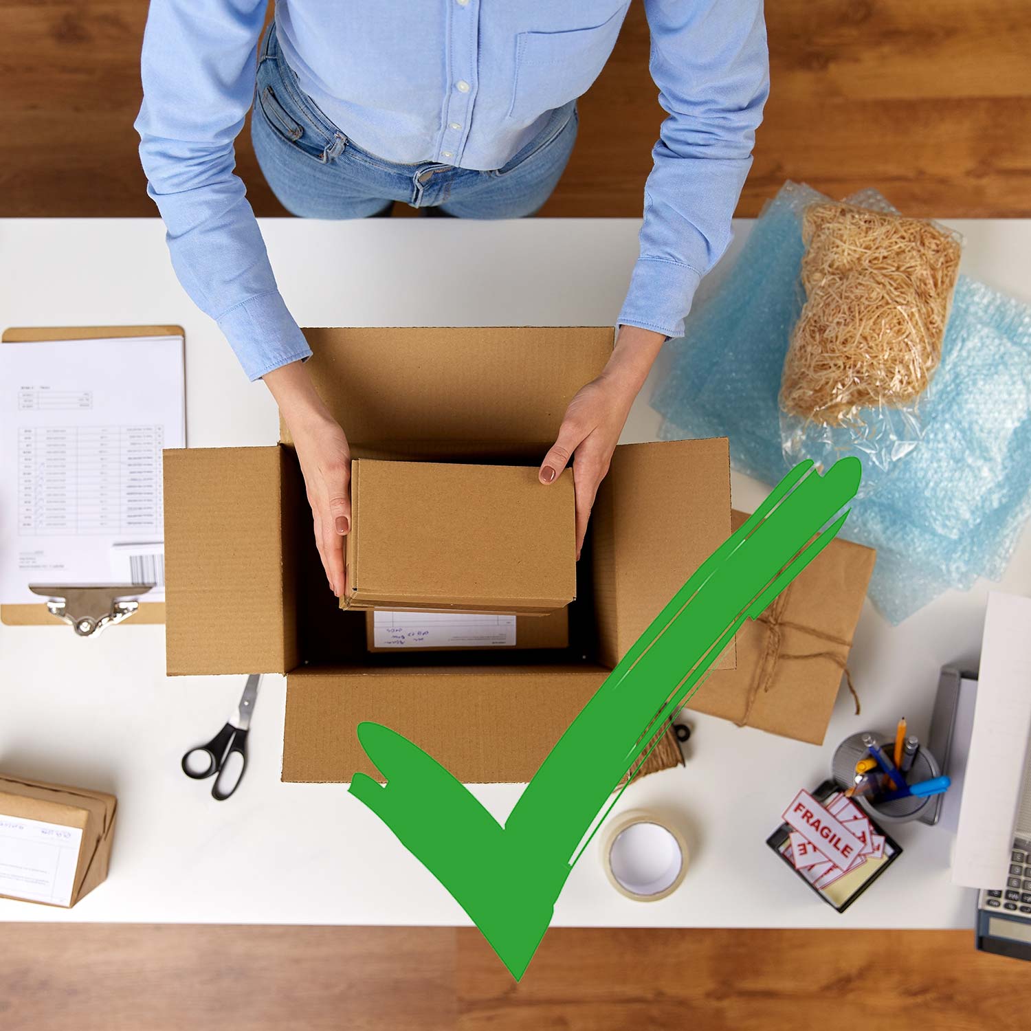 Person legt Innenverpackung in Au&szlig;enverpackung eines Pakets und gr&uuml;ner Haken ist als OK-Symboil ist zu sehen